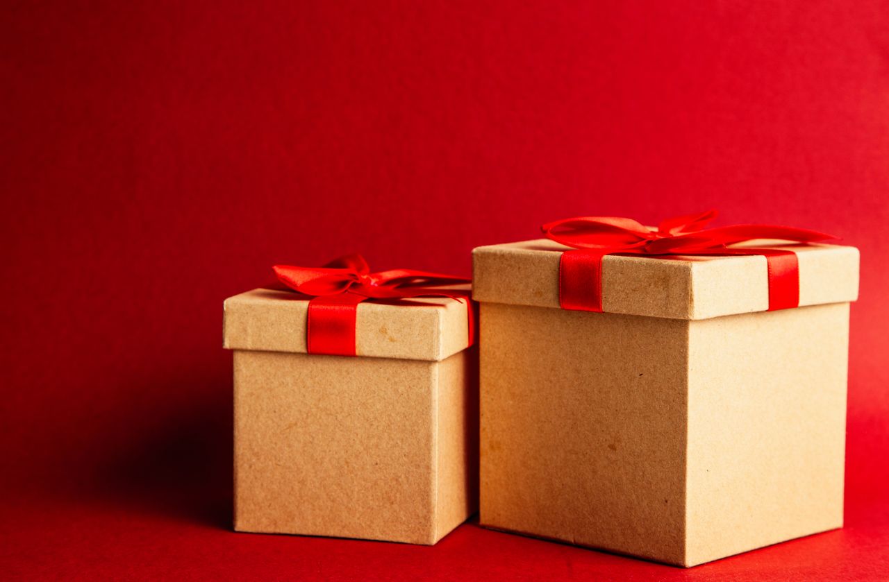 our-story Two gift boxes with red ribbons on a vibrant red background.