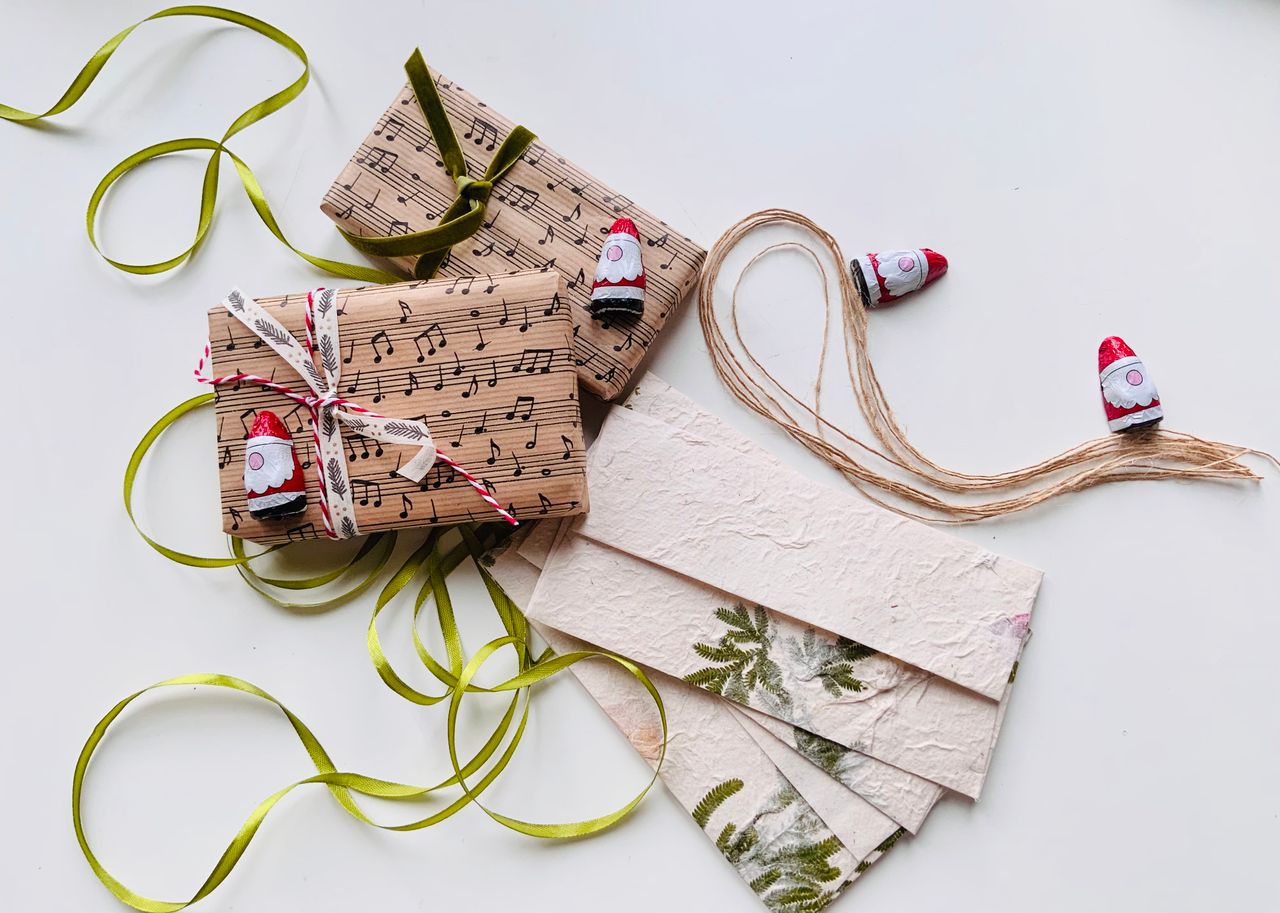 services-02 Stylish gift wrapped in musical notes paper with green ribbons and decorative gnome figures.